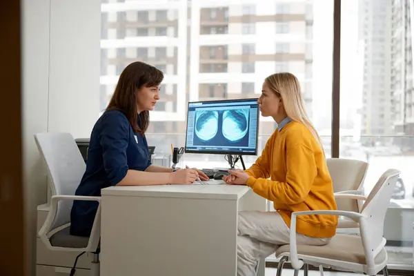 女性医師は 診察中に若い女性患者にX線スキャンを説明しました 放射線で検出された病気の診断を記述する医師 サポートと治療の処方箋を与える — ストック写真