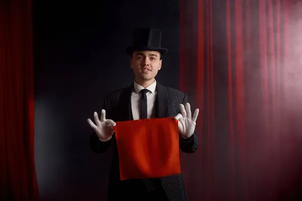在剧场舞台的神秘气氛中 年轻的男魔术师用餐巾表演魔术 烟雾弥漫 假象节目和人们的专业职业 免版税图库图片