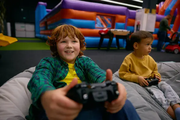 在游戏中带着惊喜和喜悦的兴奋男孩的肖像 玩电子游戏时感到震惊以赢得比赛或挑战 在儿童娱乐中心度过的愉快时光 图库图片