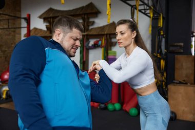 Spor salonunda kişisel koçla savunma eğitimi alan bir kadın. Rutin konsept uygulanıyor