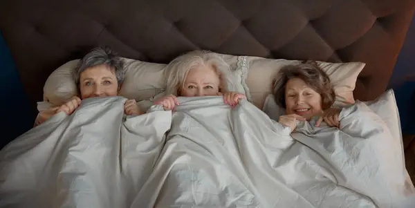 Cute Funny Elderly Woman Friends Lying Bed Blanket Enjoying Free stockbilde
