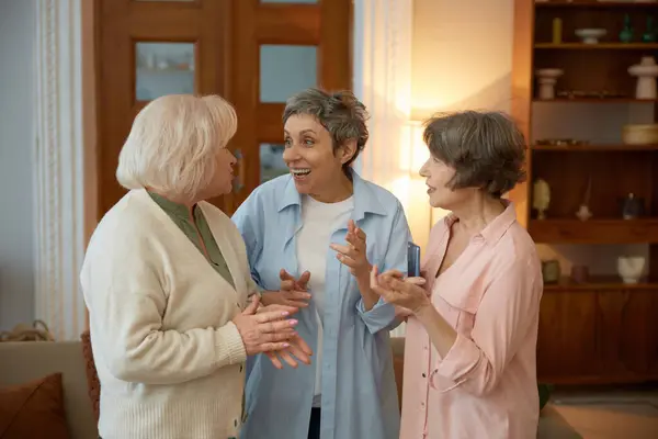 Laughing Elderly Women Friends Standing Home Living Room Senior Females stockbilde