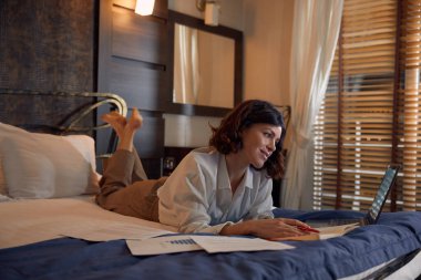 İş gezisi sırasında otel odasından internet üzerinden çalışan meşgul genç bir iş kadını. Araştırma yapan kadın girişimci, dizüstü bilgisayardaki mali rapora hazırlanıyor