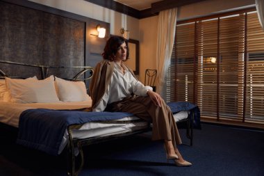 Otel odasında yatakta oturan kendine güvenen genç bir iş kadını. İş konferansından sonra rüya gören ve rahatlatan kadın yöneticiler veya şirket ortakları toplantısı