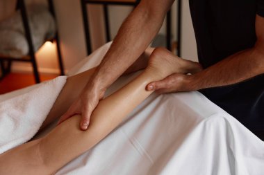 Spa salonunda kadın bacağına masaj yapan bir terapist. Kramp ağrısını iyileştiriyor. Kozmetoloji ve vücut tedavi prosedürü