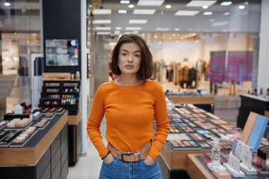 Kozmetik mağazasında genç ve çekici bir kadın. Büyük dükkanda yüzü farklı olan bir kadın.