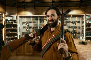 Elinde iki tüfekle duran cephane takan erkek avcının portresi. Silah dükkanı ve av mühimmatı konsepti