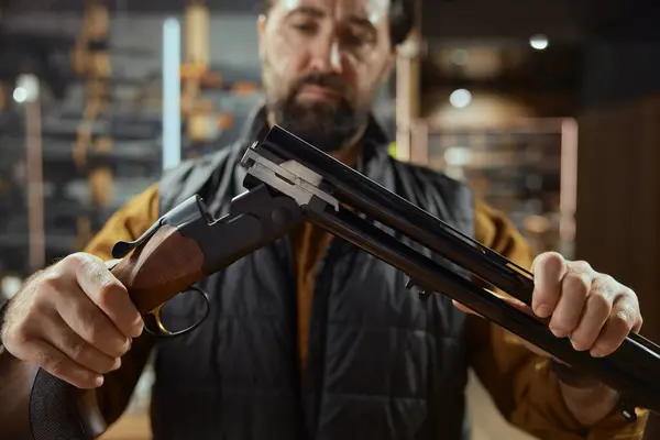 stock image Man working in weapon shop preparing high quality munitions for sale. Gun store showcase assortment with variety of equipment and special accessory