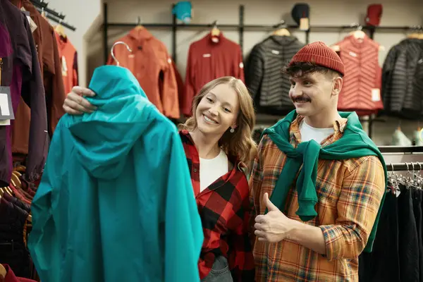 stock image Man and woman hipster couple buying activewear for winter hiking at sport shop. Male and female friends choosing jacket outwear. Boyfriend showing thumbsup confirming good choice of girlfriend