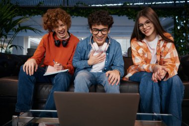 Gençlerden oluşan bir ekip iş görüntülü görüşme yapıyor. Dizüstü bilgisayar ve kulaklık kullanan gençler ofiste çalışıyor. Üç genç çalışan yeni iş projesini tartışıyor