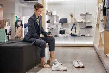 Kadın müşteri ayakkabı mağazasında yeni rahat ayakkabılar seçiyor. Alışveriş zamanı zor bir karar.