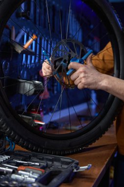 Tamirhanedeki tamirci, bisiklet frenini İngiliz anahtarıyla tamir ediyor. Tamirci arka tekerlek yedek parçasını ayarlıyor