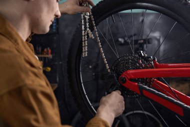 Tamirci adam dağ bisikleti tamirciliği yapıyor. Yeni yarış sezonu için yeni zincir hazırlama aracı değiştiriliyor.