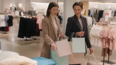 Büyük moda mağazasında alışveriş yapan mutlu genç bayan arkadaşlar. İndirim ve satış konseptiyle satın almalar