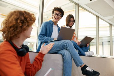 Modern ofiste dizüstü bilgisayarlarını kullanarak online para kazanan üç genç işçi. Ofis binasında çalışan bir grup genç.