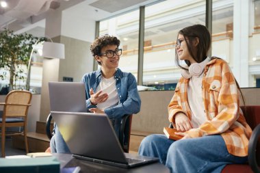 Ofiste dizüstü bilgisayar ekranına bakan bir grup zeki genç. Çevrimiçi becerilerini kullanarak ortak çalışma alanında çalışan gençler