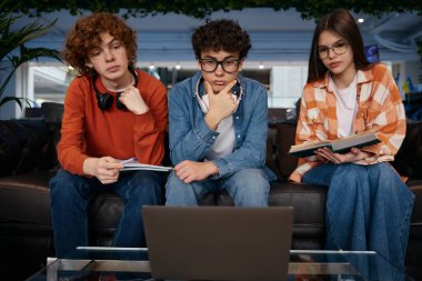 Gençler grubunun iş videosu var. Dizüstü bilgisayar ve kulaklık kullanan gençler ofiste çalışıyor. Üç genç çalışan yeni iş projesini tartışıyor