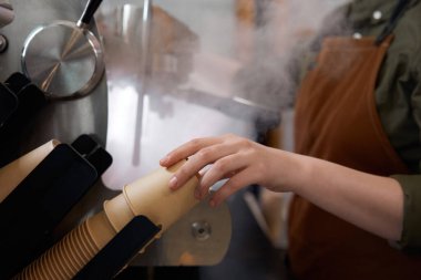 Kamu kafeteryasında kahve makinesinde kahve hazırlarken kağıt kahve fincanı alan yakın plan kadın barista.