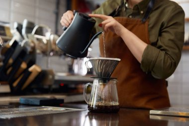 Kahve makinesinin içine kaynar su döken barista elleri. Bayan garson. Mutfaktaki müşteriye aromatik bir içecek hazırlıyor.