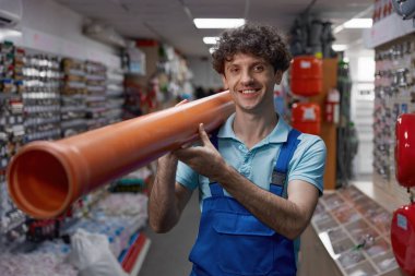 Su kaynağı ya da ısıtma sistemi için boru taşıyan gülümseyen tesisatçının bel portresi.