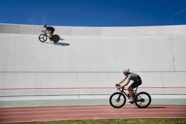 İki sağlıklı bisikletçi dışarıda sürat pistinde bisiklet üzerinde egzersiz yapıyor. Bisiklet hobisi ve eğitim etkinliği konsepti