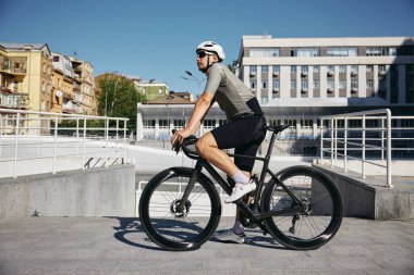 Aktif kıyafet, güneş gözlüğü ve koruyucu başlık takan iyi donanımlı erkek bisikletçi güneşli yaz günü eğitim için kentsel velodrom 'a geldi.