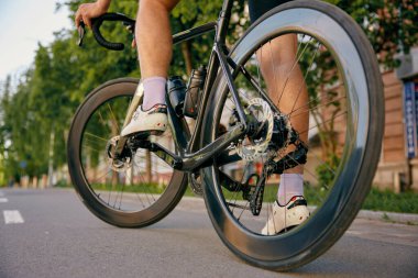 Bisiklet kuyruğu olan şehir yolunda bisiklet süren profesyonel deri ayakkabılı tanınmayan bir sporcu. Spor bisikleti tekerleklerinin yakın görüntüsü