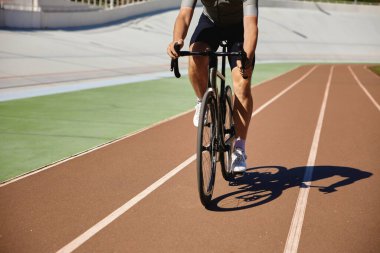 Spor kıyafetleri ve koruyucu başlık takan bisikletçi sürücüsü velodromda bisiklet sürüyor. Genç sporcu yarışma ya da maraton koşusuna hazırlanıyor. Hobi ve aktif yaşam tarzı konsepti