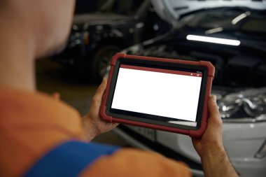 Omuz manzarası boş tablet ekranında otomatik mekanik ellerde. Otomotiv tamir atölyesinde hasarlı araba elektronik veya motorunun taranması ve teşhisi