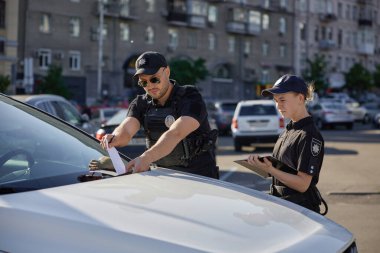 Polis devriyesi ve devriye polisi yanlış yere park ettiği için ceza kesiyorlar. Trafik kurallarının ihlalinin önlenmesi