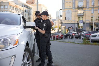 Devriye polisi ve devriye polisi trafik kontrolü sırasında ehliyet belgelerini kontrol ediyorlar.