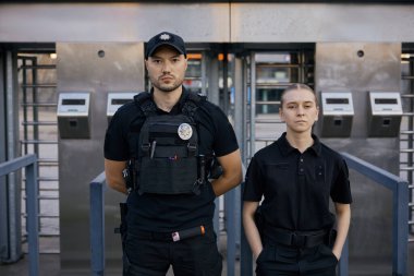 Korumalı kurşun geçirmez yelek giyen çeşitli silahlı polisler metro girişinde devriye geziyorlar.
