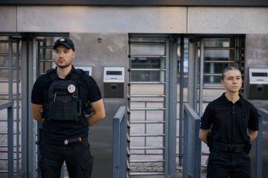 Korumalı kurşun geçirmez yelek giyen çeşitli silahlı polisler metro girişinde devriye geziyorlar.