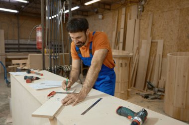 Marangoz atölyede mobilya inşaatı sırasında cetvelle tahta ölçüsü alıyor. Ev yenileme, yenileme projesi ve ahşap işçiliği konsepti