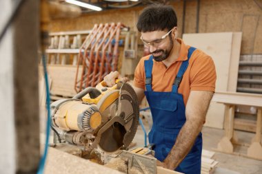 Marangoz, atölyede testere ustalığıyla çalışıyor. Ahşap mobilya imalatı ustası için profesyonel ekipman.