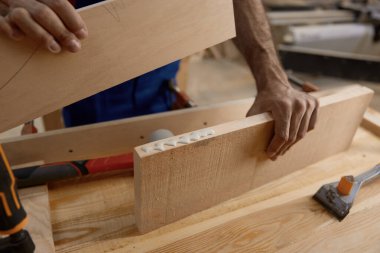 Erkek esnaf, tezgahta çalışan tutkal kullanarak tahta parçaları tutuyor ve birleştiriyor. Sanatçılık ve marangozluk stüdyosu konsepti