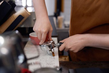Kahve tezgahında kahve yapan kadın görüntüsü. Elinde kahve makinesi ekipmanı olan kadınların yakın görüntüsü. Yiyecek ve içecek servis konsepti