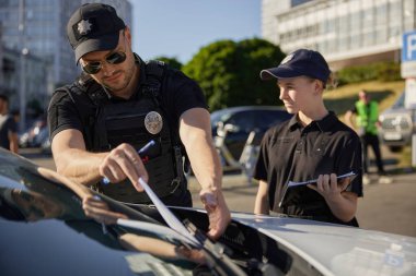 Devriye polisi ve devriyeci yanlış yere park ettiği için ceza kesiyor. Trafik kurallarının ihlalinin önlenmesi