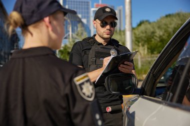 Polis memurları park ihlalinden trafik cezası yazıyor. Sokak güvenliği ekibi iş başında.