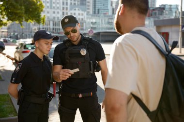Ciddi devriye polisi ve polis memuru şehir sokaklarındaki vatandaşın kişisel belgelerini inceliyor.