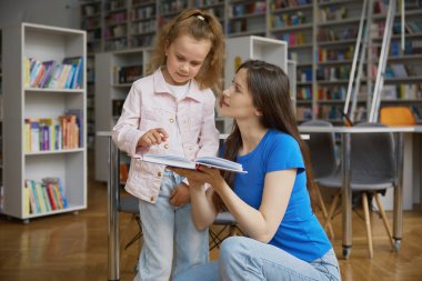 Mutlu anne ve kız çocuk kitapçı geçmişi üzerinden. Anne ve anaokulu çocuğu kitaplarını mağazaya koymuşlar.