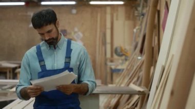 Ahşap işçisi, marangozluk atölyesinin arka planında duran tahtayı seçiyor. Ahşap işçiliği ve mobilya üretim kavramı