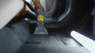 Araba yıkama servisi çalışanı toz ve kiri temizliyor ve profesyonel ekipman uygulayan arka yolcu koltukları oluşturuyor.