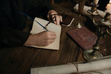 Ortaçağ keşiş tarihçisinin karanlık manastır hücresinde mum ışığı altında antik kutsal el yazması yazması.