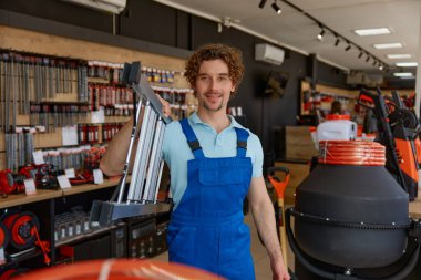 İnşaatçı hırdavatçıdan yüksek binalar için çelik merdiven alıyor. Tamirci, DIY mağazasında inşaat merdivenlerini seçiyor.