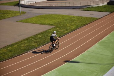 Bisikletçi sportif giysiler giyer, antrenmanların keyfini çıkarır, sürat pistinde uzaktan bisiklet sürerler. Profesyonel spor ve hobi eğlence konsepti