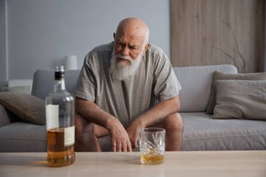 Yaşlı adam evde tek başına içki içiyor. İçki zararlı bir alışkanlık ve alkol bağımlılığı