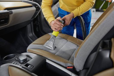 Erkek oto yıkama servisi çalışanı toz ve kiri temizliyor ve profesyonel ekipman uygulayan koltuklar oluşturuyor.