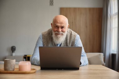 Üst düzey adam internette dizüstü bilgisayar kullanıyor ya da evdeki sosyal medyada iletişim kuruyor. Yaşlılar ve modern teknoloji kavramı