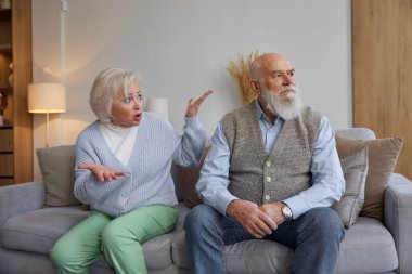 Mutsuz son sınıf çifti, somurtkan suratlarıyla sessizce kanepede oturuyor. Evlilik krizi, emeklilik ve boşanma